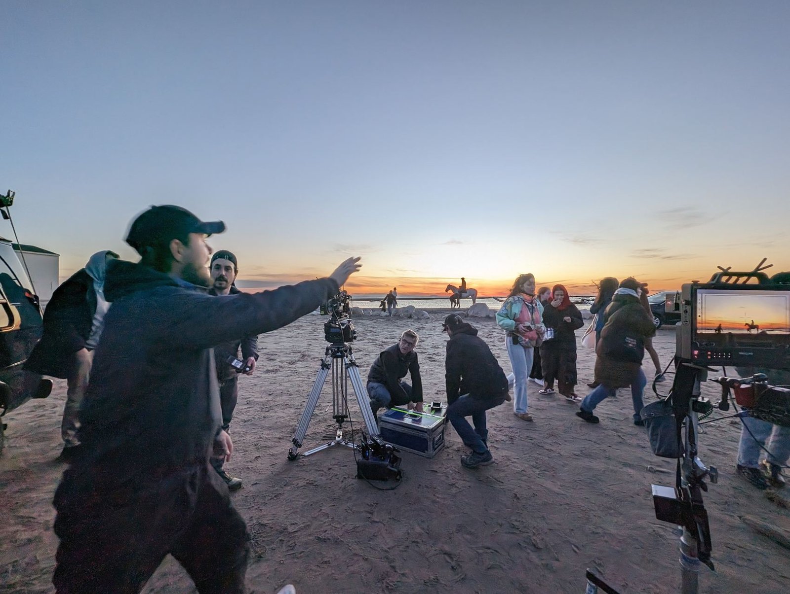 Tournage sur une plage au coucher du soleil, cavalier à l'horizon