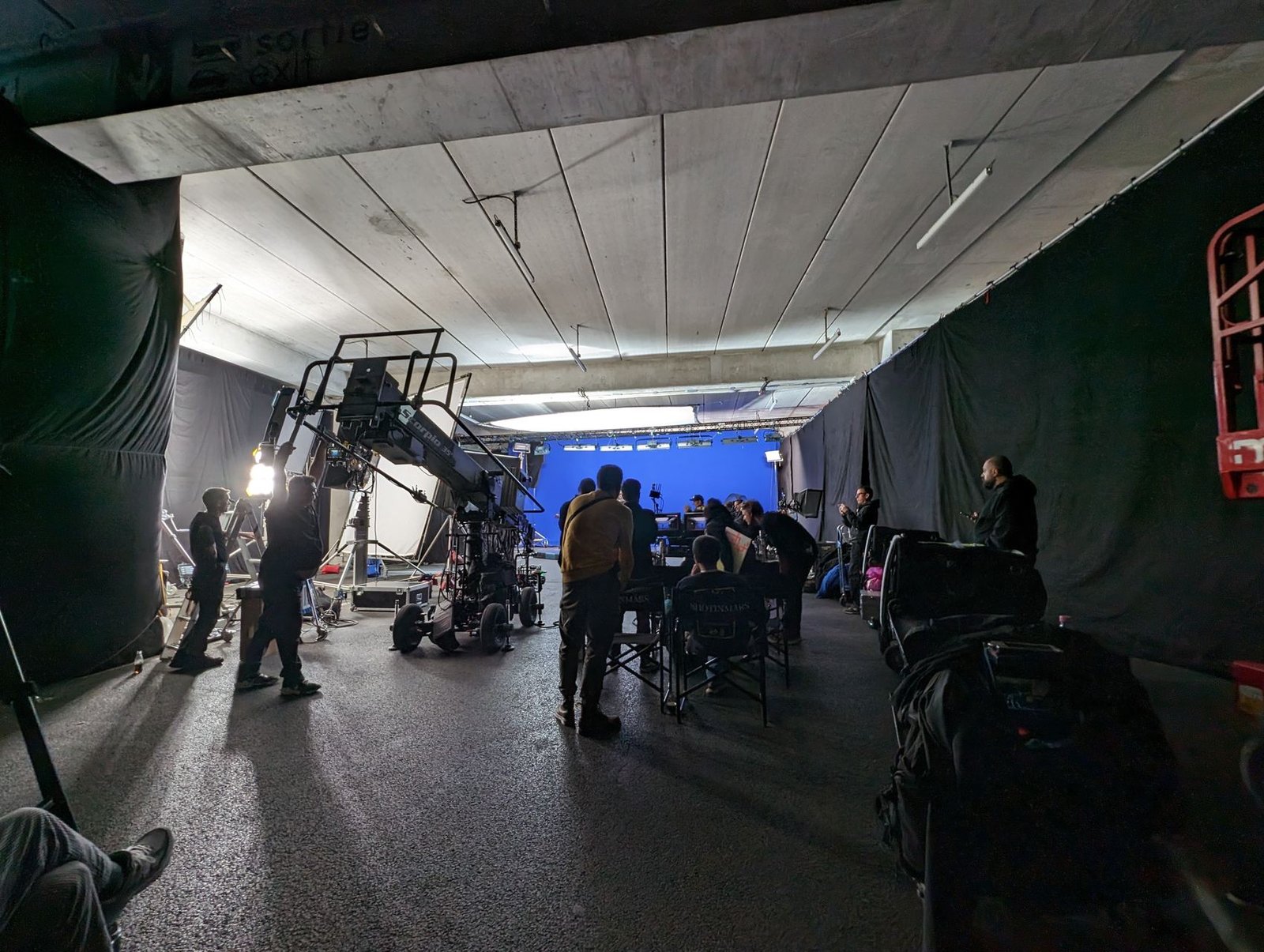 Grue Scorpio et équipe devant un fond bleu en studio, projecteurs allumés